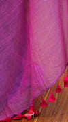 Close-up of a pink fabric with tassels on a wooden surface