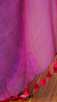 Close-up of a pink fabric with tassels on a wooden surface