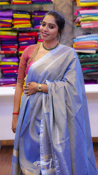 Woman in a light blue saree with a colorful background of fabric