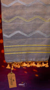 Textile with zigzag pattern and tassels, branded 'Tejashi', on a dark background.