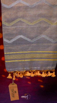 Textile with zigzag pattern and tassels, branded 'Tejashi', on a dark background.