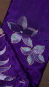Purple fabric with floral embroidery on a brown background