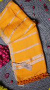 Yellow towel with white stripes and a tag on a textured surface with pink flowers.