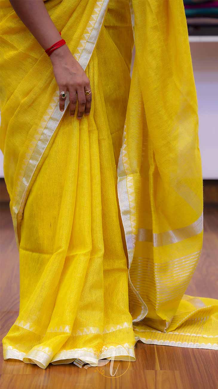 Yellow saree with white border on a wooden floor