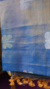 Blue fabric with white floral patterns and decorative elements on a purple background