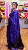 Woman wearing a blue saree with a pattern of gold dots in a fabric store.
