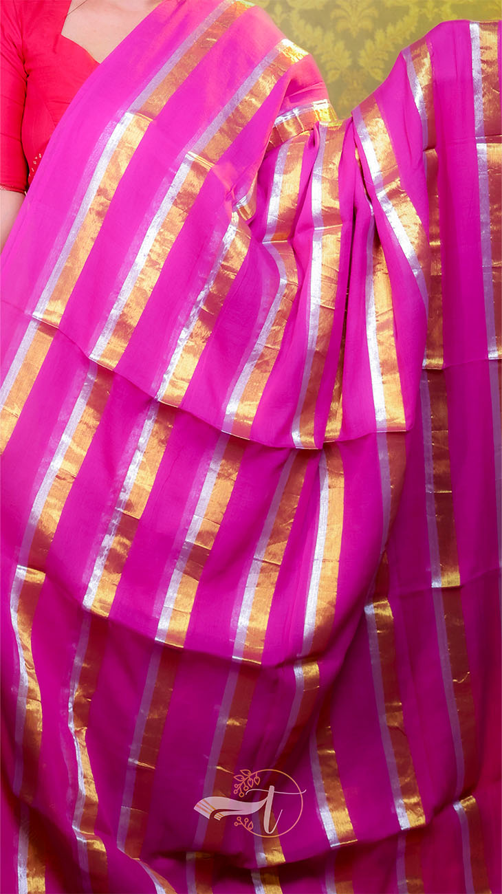 Pink saree with gold stripes draped over a person, with a blurred background.