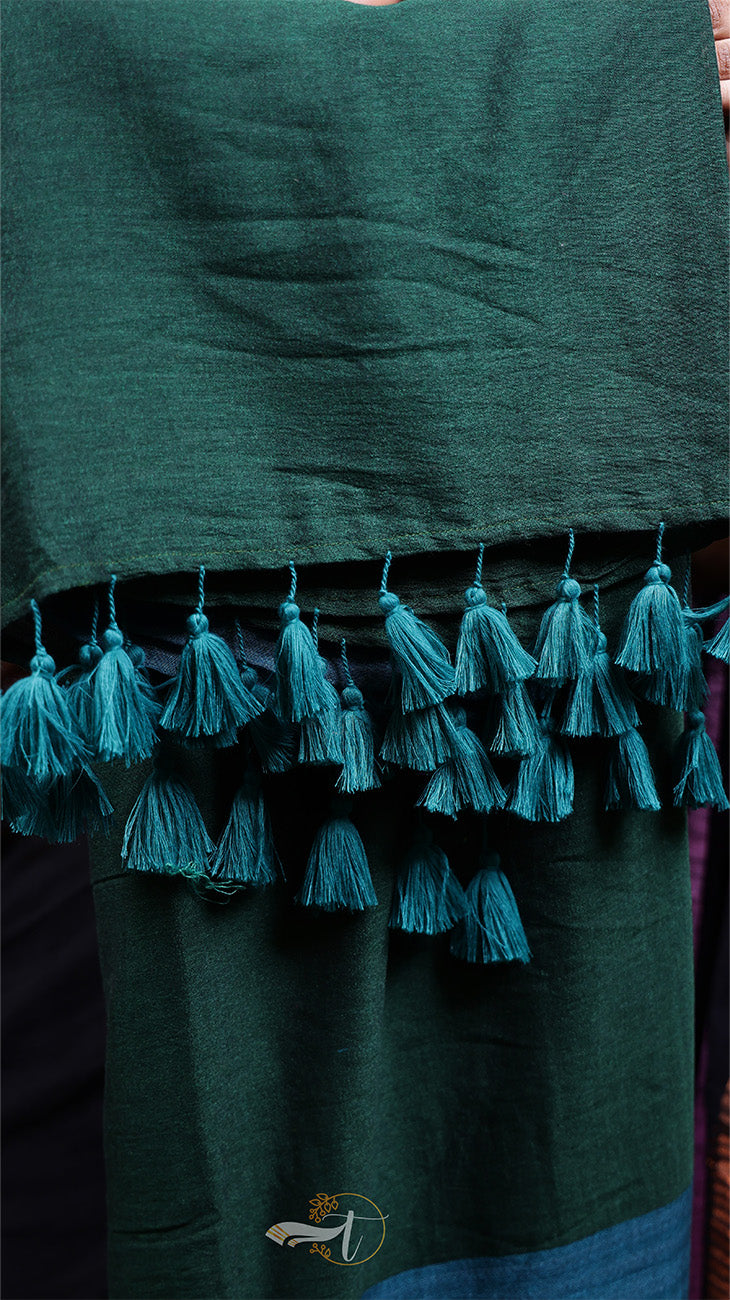 Dark green fabric with tassels on a plain background