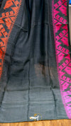 Black fabric with red and pink geometric patterns on a wooden surface