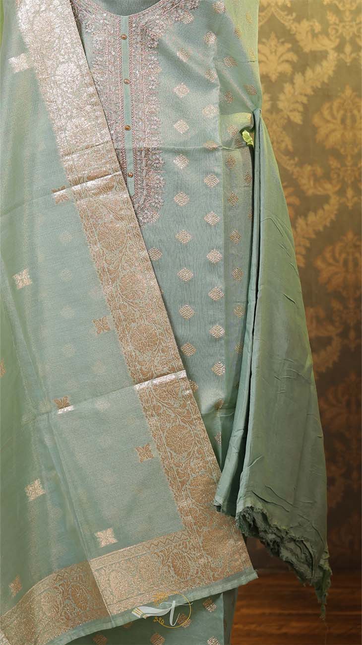 Light blue saree with gold patterns on a textured wall background