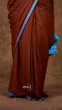 Brown saree with blue border and floral ends on a brown background