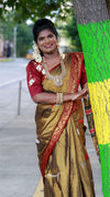 Woman in traditional attire standing next to a tree with green and yellow paint.