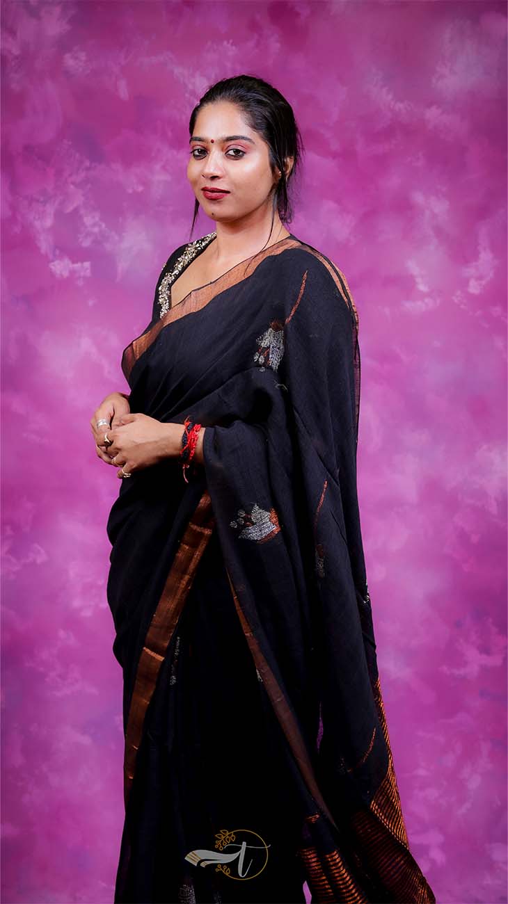Woman in a black saree with gold border against a pink and purple gradient background