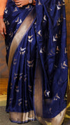 Blue saree with white patterns held by a person against a wooden floor background