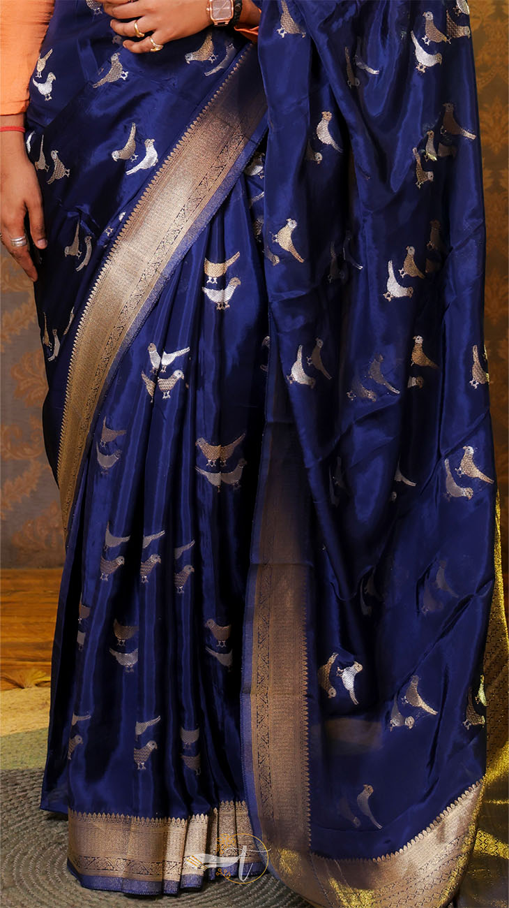 Blue saree with white patterns held by a person against a wooden floor background