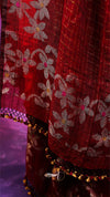 Close-up of a red fabric with floral patterns and decorative elements.