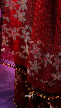 Close-up of a red fabric with floral patterns and decorative elements.