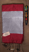 Striped red and gray fabric with a tag and decorative item on a brown background