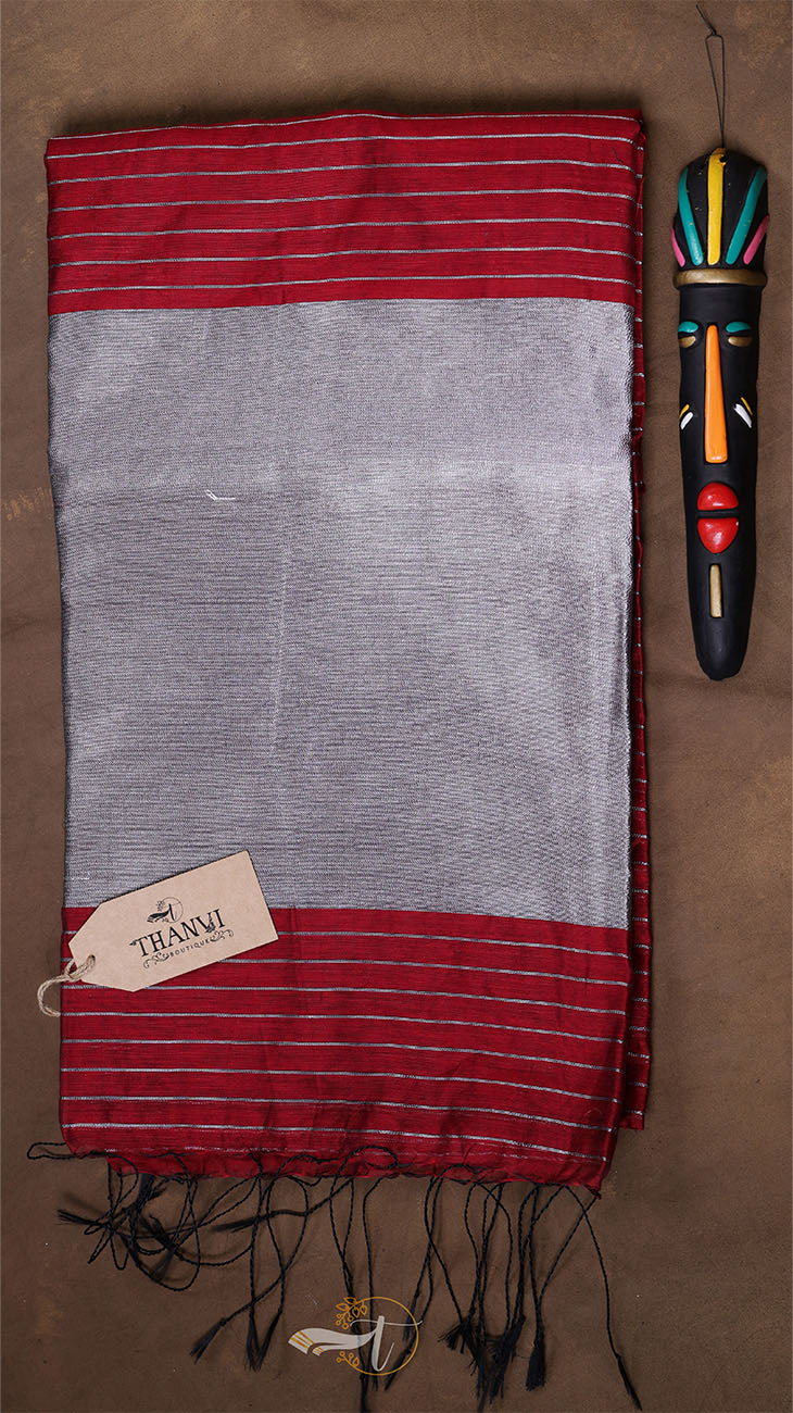 Striped red and gray fabric with a tag and decorative item on a brown background