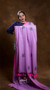 Woman wearing a purple embroidered scarf with tassels on a brown background