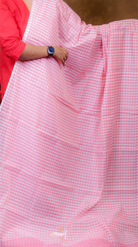 Person holding a pink checkered fabric with a blurred background