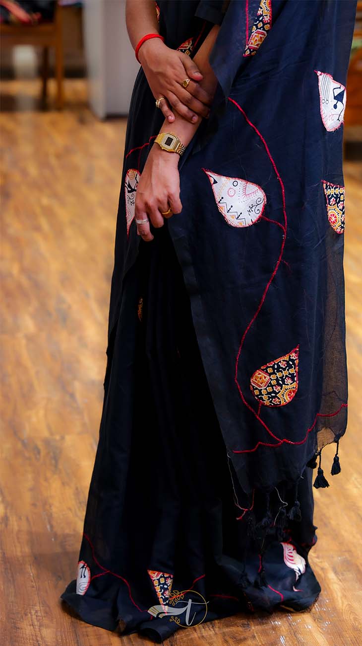 Black saree with colorful patterns on a wooden floor
