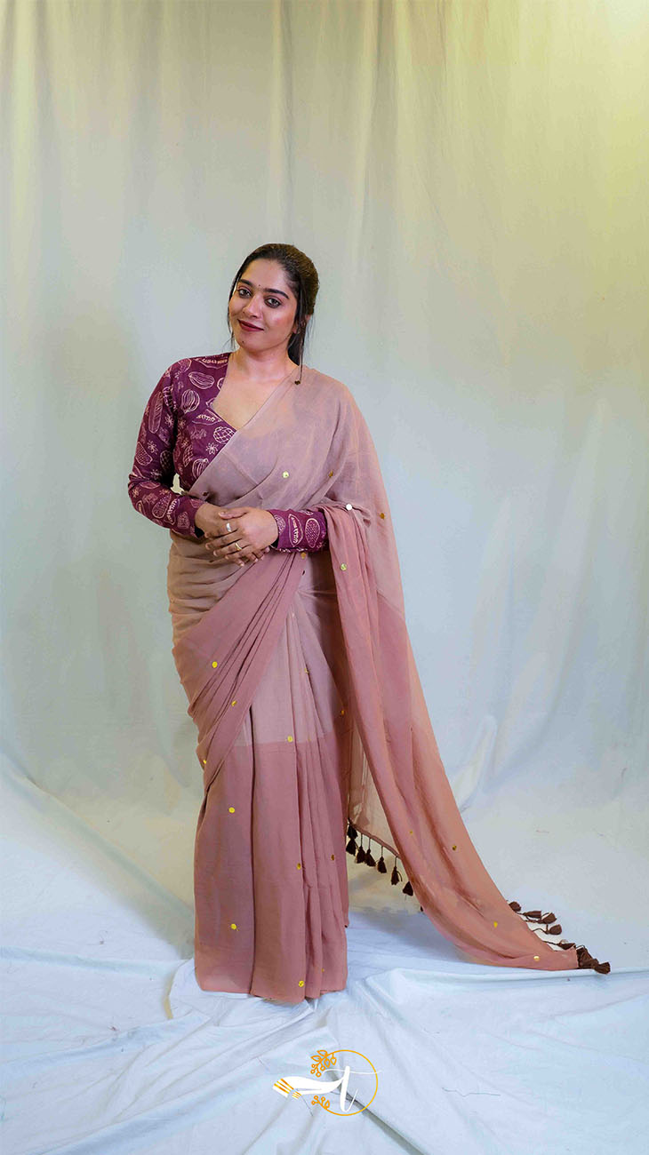 Woman wearing a saree with a matching blouse against a white background