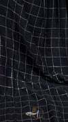 Close-up of a black checkered fabric with a small logo on a dark background
