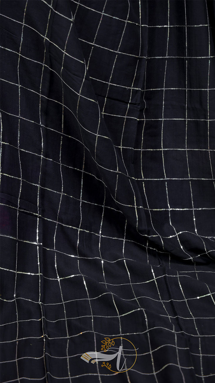 Close-up of a black checkered fabric with a small logo on a dark background