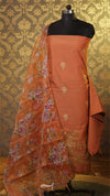 Orange saree with floral patterns on a mannequin against a patterned wall.