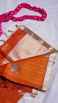 Orange saree with gold border and pink floral decorations on a light gray background