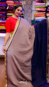 Woman holding a beige saree with a colorful fabric background