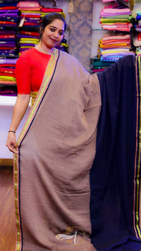 Woman holding a beige saree with a colorful fabric background