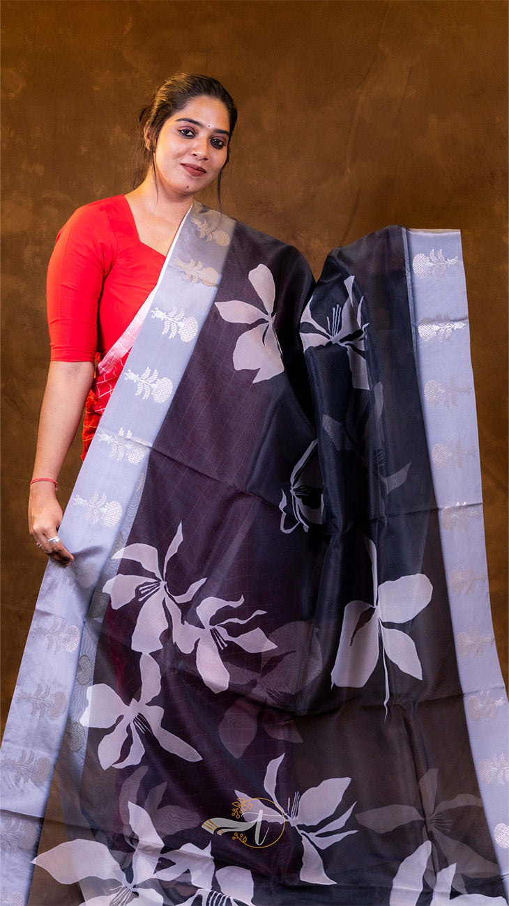 Woman holding a dark floral saree against a brown background