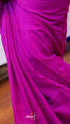 Close-up of a bright pink fabric with folds on a wooden floor.