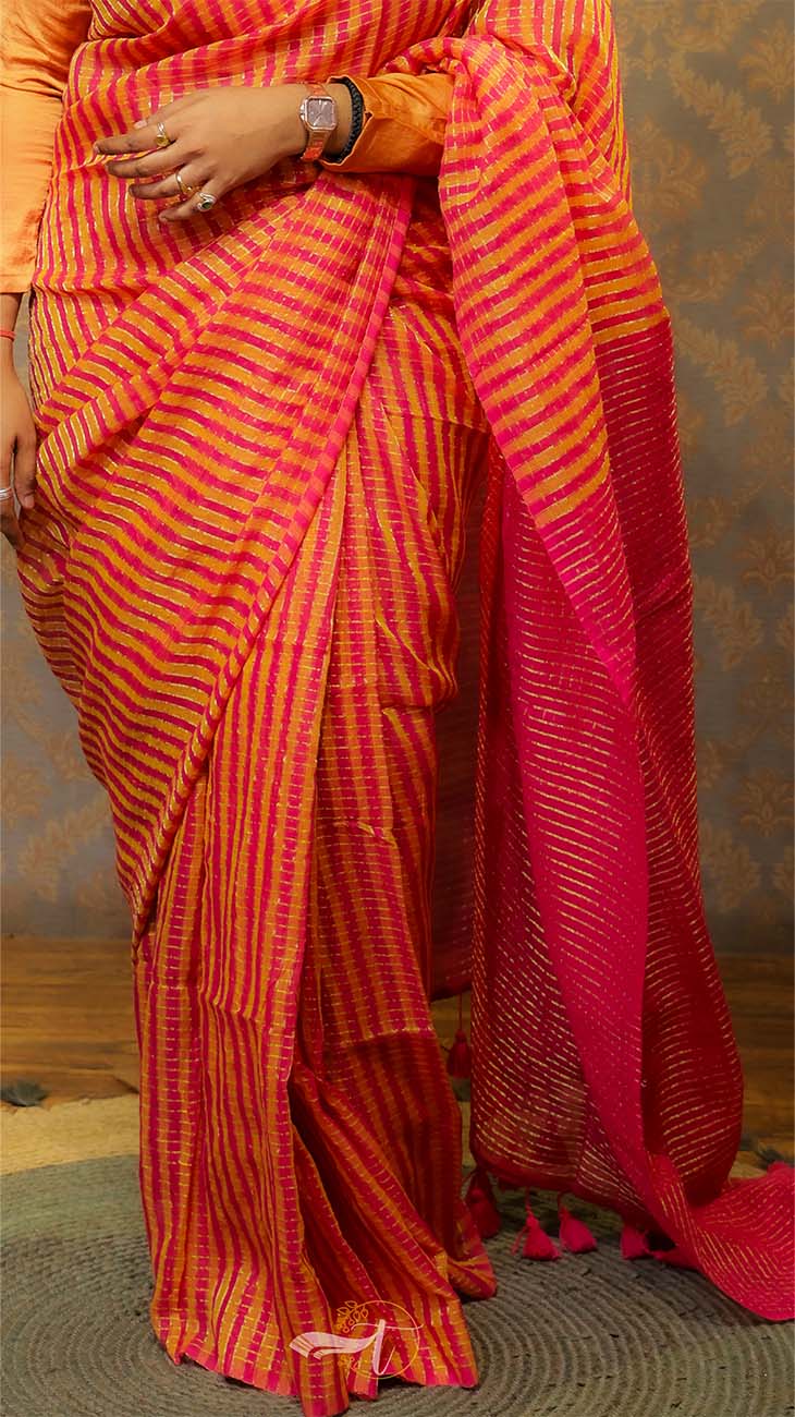 Woman wearing a red and orange striped saree with a patterned background
