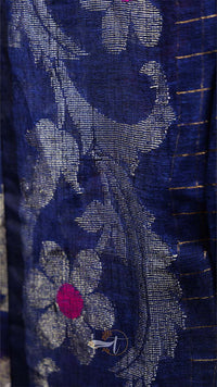 Close-up of a blue fabric with floral patterns and a pink flower.