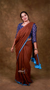 Woman wearing a brown saree with blue blouse against a brown background