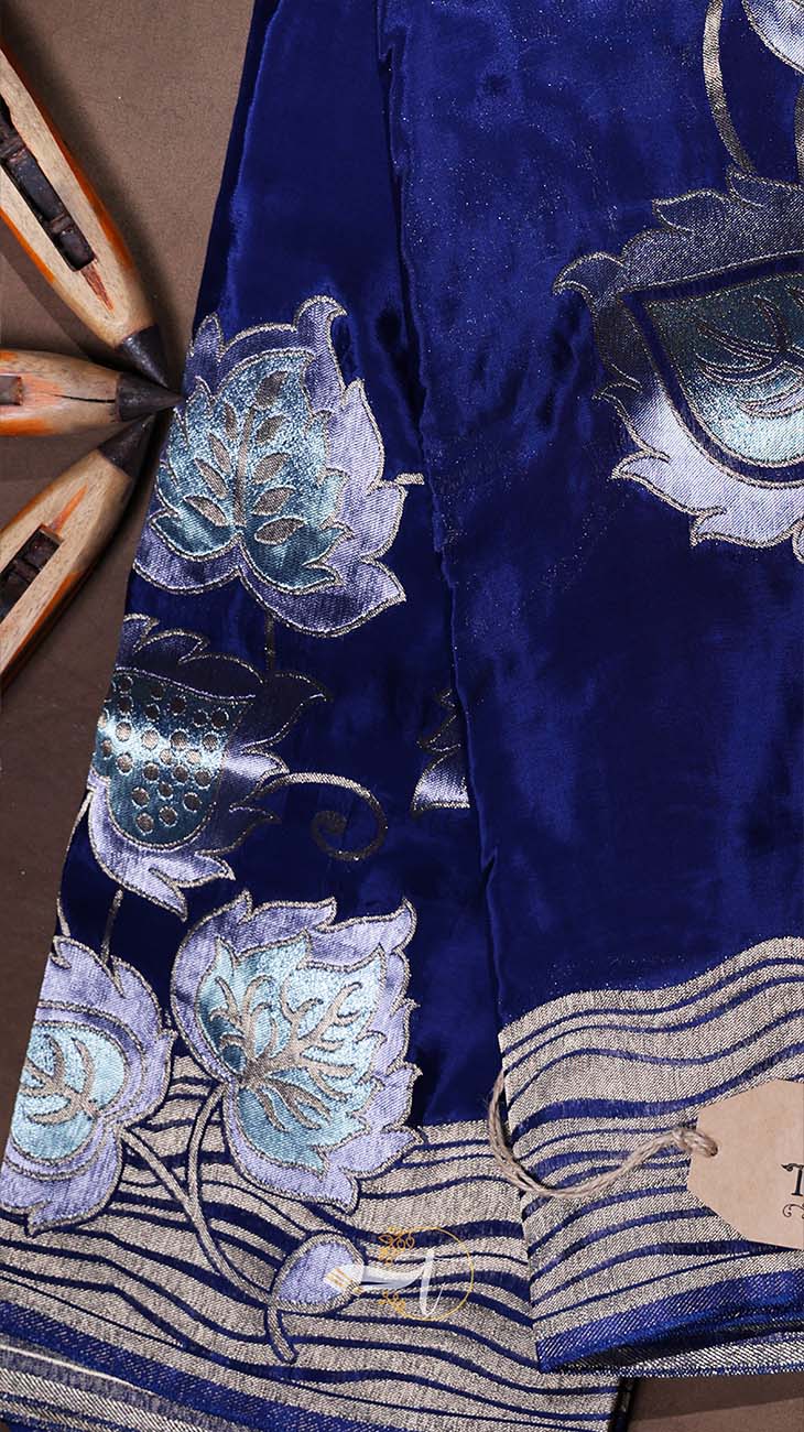 Blue fabric with silver floral embroidery on a brown background