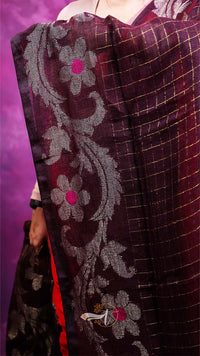 Close-up of a dark purple fabric with floral embroidery on a vibrant purple background
