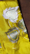 Yellow fabric with silver floral embroidery on a brown background