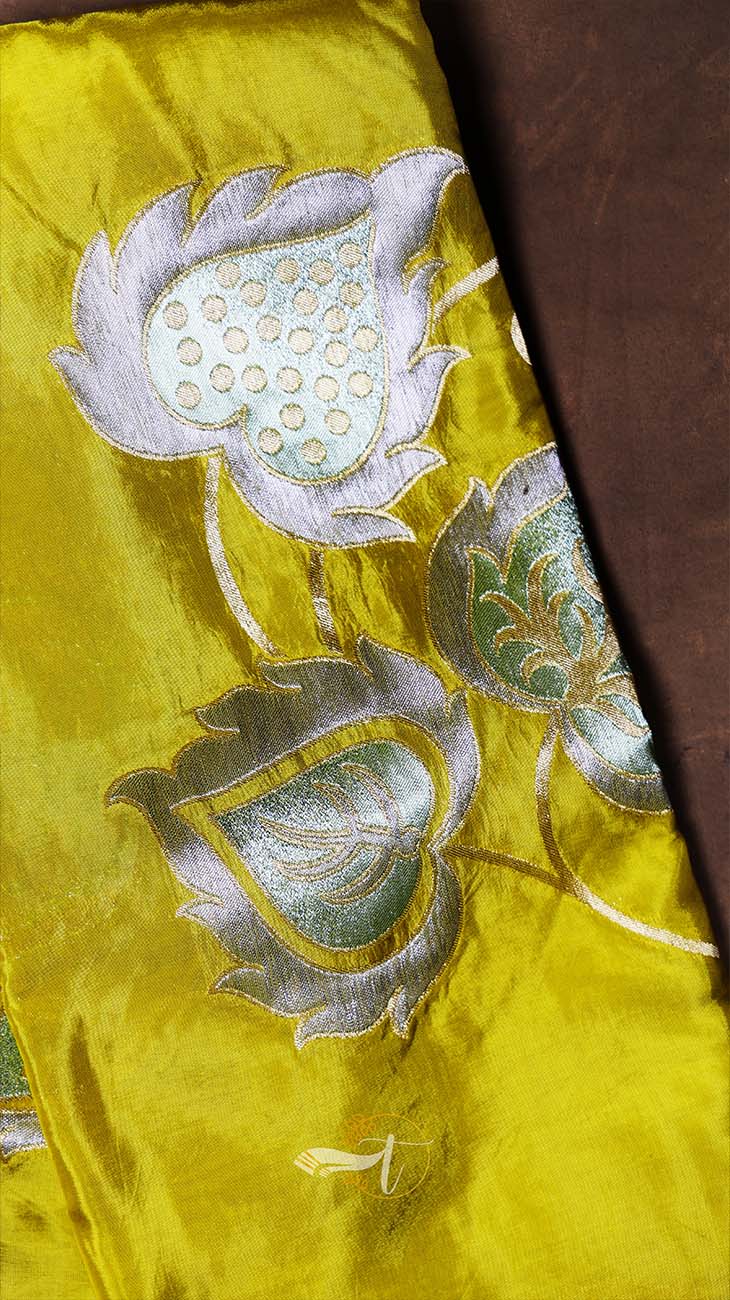 Yellow fabric with silver floral embroidery on a brown background