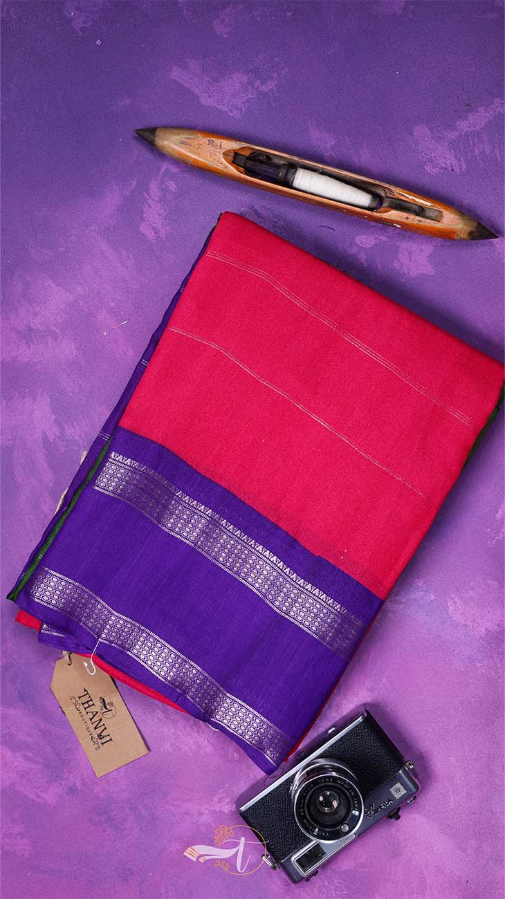 Red and purple saree with a loom and camera on a purple background