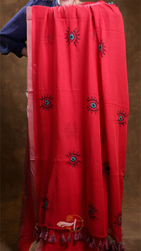 Red fabric with black embroidered designs on a brown background
