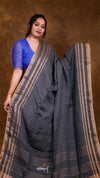 Woman holding a dark gray saree with a brown background