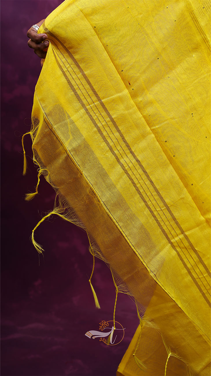 Close-up of a yellow fabric with intricate patterns on a dark background
