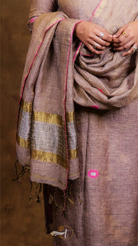 Person wearing a brown saree with gold stripes on a dark background