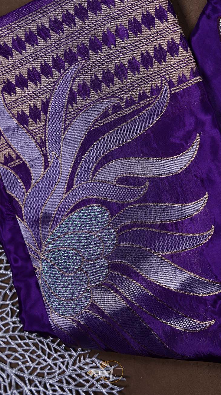 Close-up of a purple fabric with intricate silver embroidery on a brown background