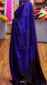 Blue saree with gold patterns draped over a person, with a blurred background of a store.