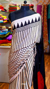 Saree with black and white pattern on a mannequin against a colorful fabric background
